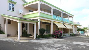 A two-story building with a balcony, a covered entrance, and a satellite dish. - Flic En Flac: Cosy Apartment in a nice setting (Flic en Flac)