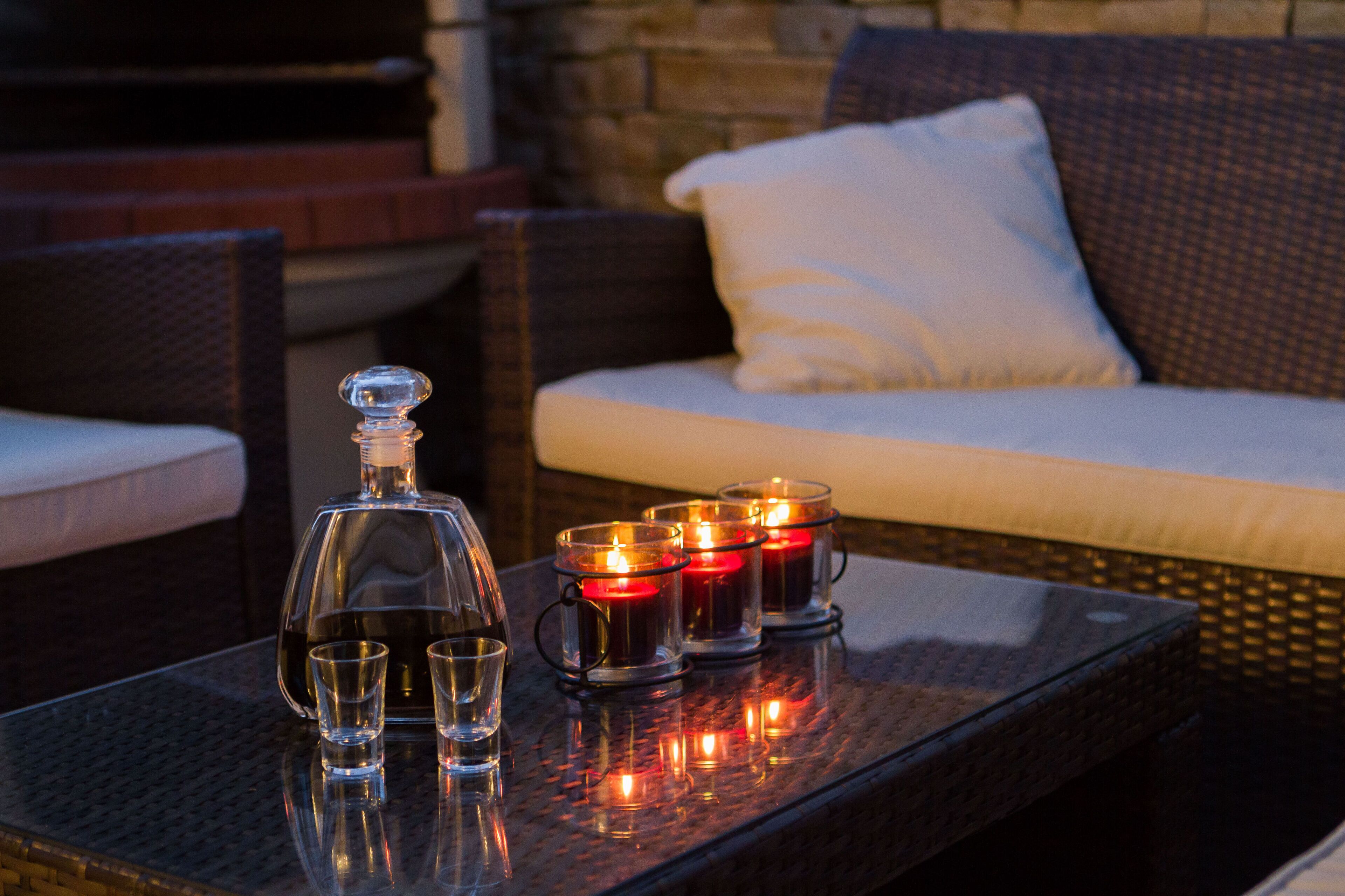 A glass-top table with a decanter, shot glasses, and lit candles.