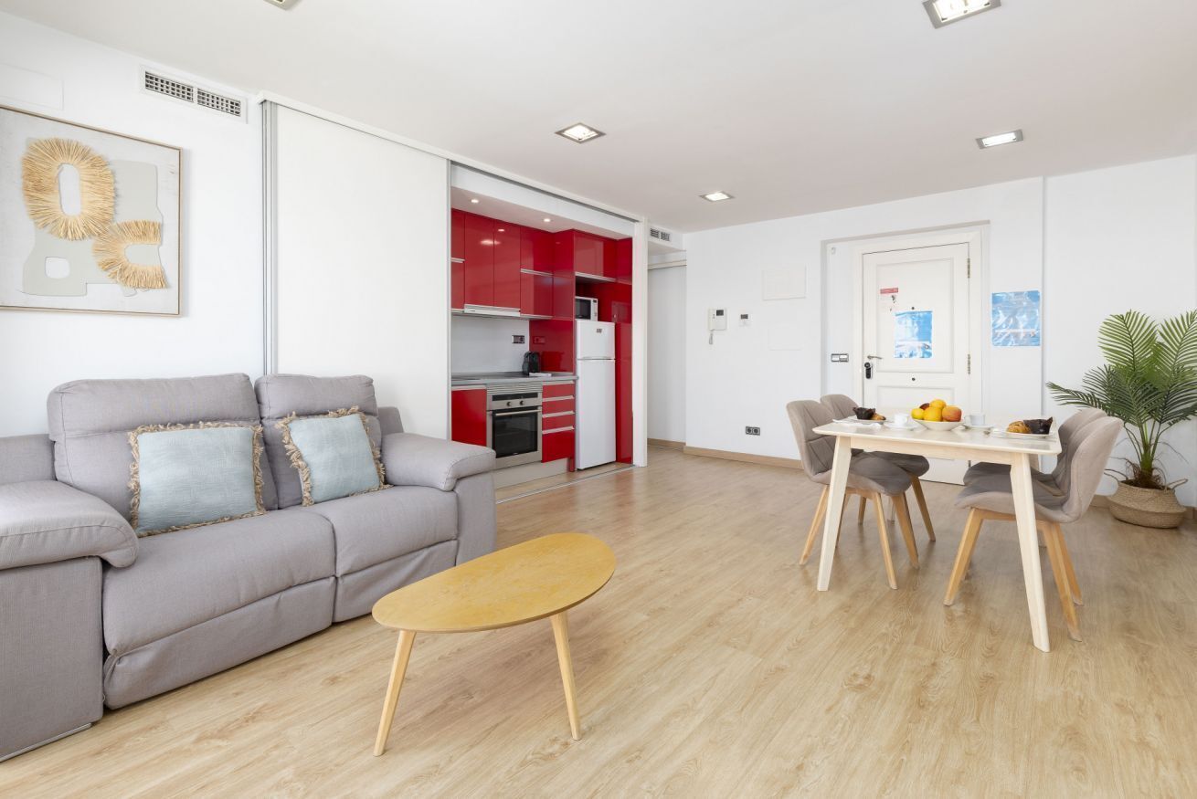 Una sala moderna con un sofá gris, una mesa de centro de madera y un comedor con mesa y sillas.