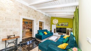 A spacious living room with a stone wall, a green accent wall, and a large TV. - Amazing home in Kastel Sucurac (Kastel Sucurac)