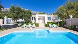 A modern pool area with a clear view of the pool, lounge chairs, and a building with a large entrance. - Amazing home in Kastel Sucurac (Kastel Sucurac)