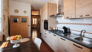 A kitchen with wooden cabinets, a gas stove, and a sink. - Casa Conchiglia: Authentic Seafront Apartment (Monopoli)