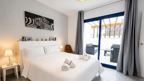 Hotellihuone, jossa on sänky, työpöytä, tuoli, lamppu, taulu seinällä ja näkymä ikkunasta.