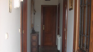 Un couloir avec une porte en bois au fond, un radiateur sur la droite et un meuble sur la gauche.