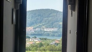 Un chien est allongé sur un sol carrelé, près d’un seuil de porte, d’où l’on aperçoit une colline et des bâtiments.