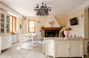 A spacious kitchen with a dining area, a fireplace, and a chandelier.