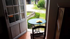 A room with a wooden door, a round table with a chair, and a book on the table. - Holiday rental house with farmyard and garden near Cognac. (Les Métairies)