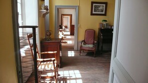 A hallway with a wooden floor, a chair, a table, and a shelf with decorative items. - Holiday rental house with farmyard and garden near Cognac. (Les Métairies)