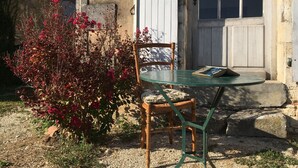 A wooden chair and table outside a building with a white door and window. - Holiday rental house with farmyard and garden near Cognac. (Les Métairies)