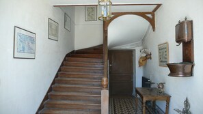 A wooden staircase with a patterned floor, a wall-mounted lantern, and a rustic wall decor including a hat and a copper pot. - Holiday rental house with farmyard and garden near Cognac. (Les Métairies)