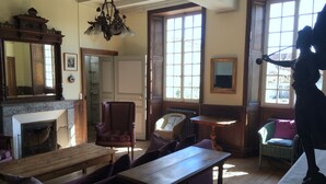 A traditional room with a fireplace, wooden furniture, and large windows. - Holiday rental house with farmyard and garden near Cognac. (Les Métairies)
