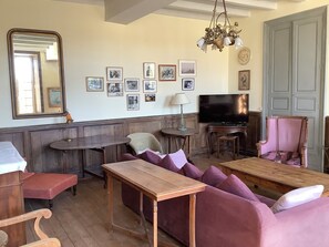 Een woonkamer met een houten bank, een bankstel, een televisie en een kroonluchter.