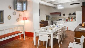 A dining area with a long table set for multiple people, a bench with a red cushion, and a kitchen in the background. - Amazing home in Piegaro PG (Piegaro PG)