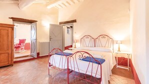 A bedroom with a bed, two bedside tables, a wooden wardrobe, a rocking chair, and a radiator. - Amazing home in Piegaro PG (Piegaro PG)