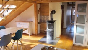 A cozy kitchen with a wooden ceiling, a built-in stove, and a dining area with a table and chairs. - Close to the mountains! (Pfronten)