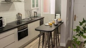 A modern kitchen with a black countertop, stainless steel appliances, and a wooden floor. There is a dining area with a table and chairs. - VALTOUR New apartment Downtown+Wifi+A/C+Terrace (Valladolid)