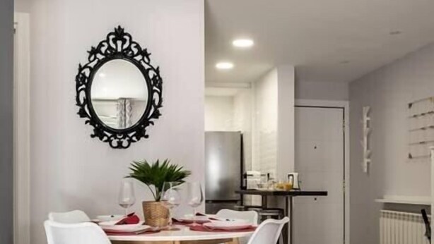 A modern dining area with a round table, white chairs, and a decorative mirror on the wall. - VALTOUR New apartment Downtown+Wifi+A/C+Terrace (Valladolid)
