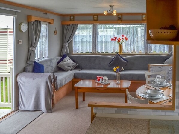 Una sala de estar acogedora con un sofá, una mesa de centro y un comedor con una mesa dispuesta para dos personas.