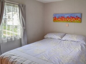 Un dormitorio con cama, ventana con cortinas y un cuadro en la pared.