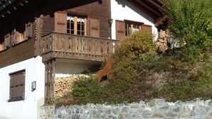 A traditional chalet with a stone foundation, wooden balcony, and a rustic aesthetic.
