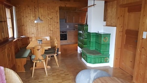 A cozy cabin interior with a wooden dining table, chairs, a kitchen area, and green storage units.