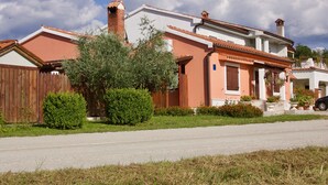 Una casa de dos pisos con techo de tejas rojas, chimenea de ladrillo y cerca de madera.