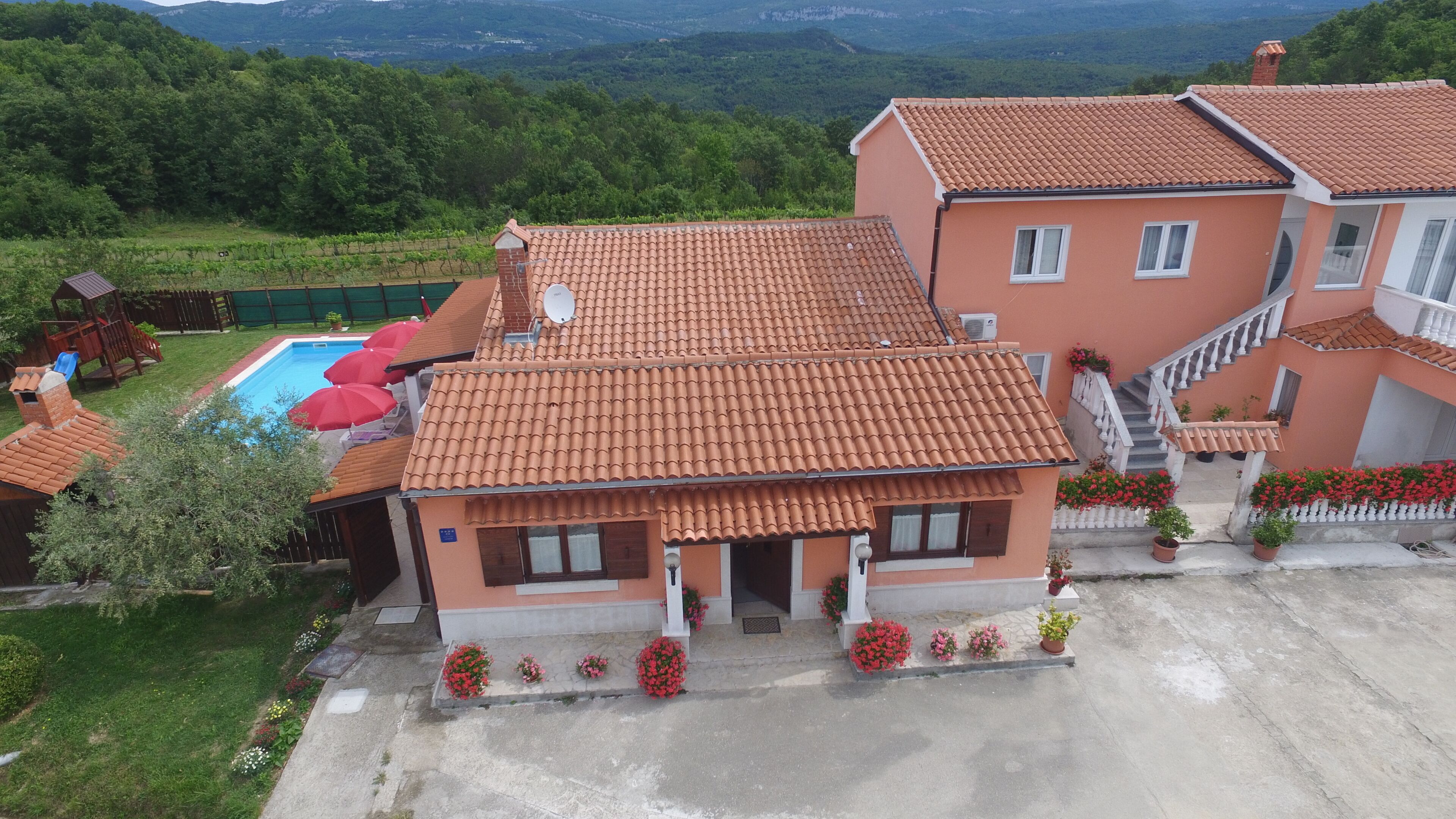 Une maison à deux étages, avec un toit recouvert de tuiles, une piscine et un jardin fleuri.
