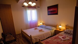 Una habitación de hotel con una cama, una silla, una mesita de noche, una lámpara y un cuadro en la pared.