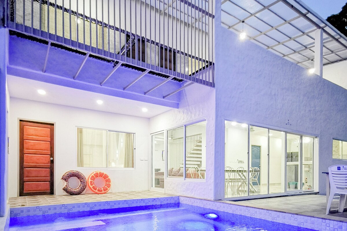 Et moderne hus med swimmingpool, balkon og trappe op til en øvre etage.