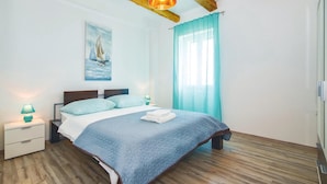A bedroom with a bed, a nightstand, a lamp, a painting, and a window with curtains. - 3 bedroom nice home in Stanici (Stanici)