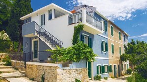 A two-story building with a stone foundation, a balcony with a metal railing, and a staircase leading to the upper floor. - 3 bedroom nice home in Stanici (Stanici)