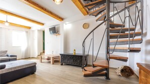 A modern living room with a spiral staircase, wooden flooring, a sofa, a coffee table, and a TV mounted on the wall. - 3 bedroom nice home in Stanici (Stanici)