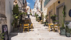 Eine schmale Straße mit Außenplätzen, Blumentöpfen und einer Treppe, die zu einem Gebäude führt.