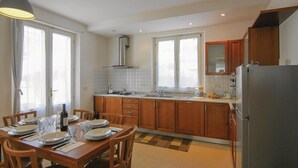 A modern kitchen with wooden cabinets, a stainless steel sink, and a built-in oven. There is a dining table set with plates and cutlery. - Lovely home in Torre del Lago Puccini (Torre del Lago Puccini)