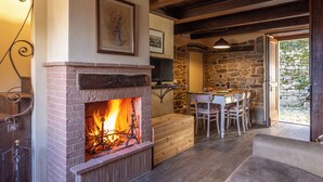Une pièce chaleureuse avec une cheminée, des murs en pierre, une table à manger et des chaises.