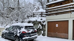 Ein schwarzer SUV vor einem Gebäude mit Holzdach und einer Garagenöffnung.