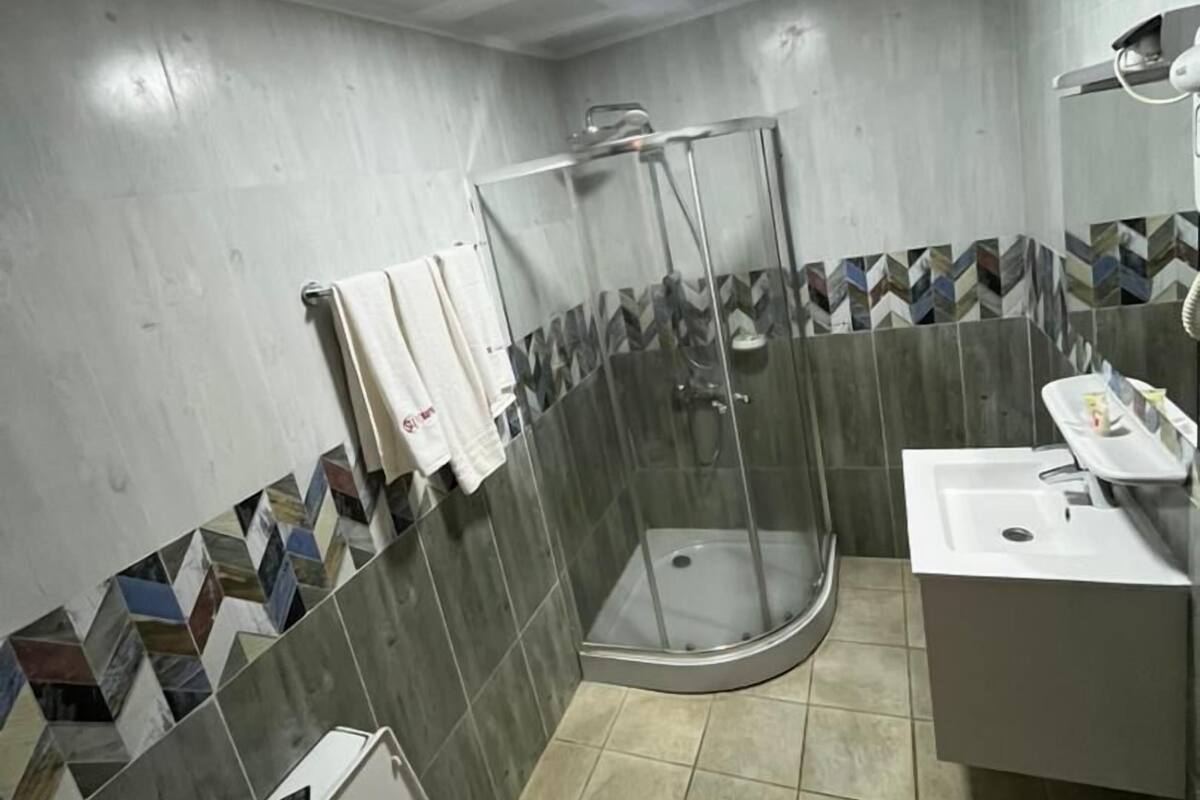 Um banheiro com chuveiro, vaso sanitário e pia.