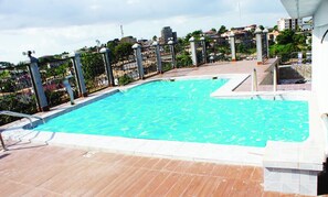 Enjoy a refreshing swim in our rooftop pool surrounded by a decorative fence and a stone border.