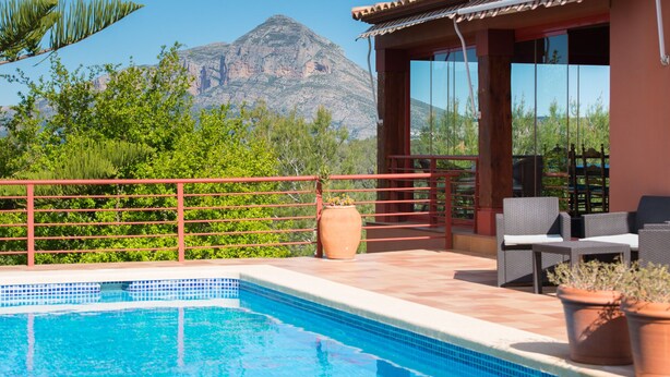 A pool area with a view of a mountain, outdoor seating, and a red railing. - LUXURY AIR-CONDITIONED VILLA WITH SEA VIEW 5 BED 10 PEOPLE WI FI (Jávea)
