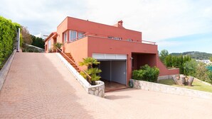 A modern house with a red facade, a paved driveway, and a garage. - LUXURY AIR-CONDITIONED VILLA WITH SEA VIEW 5 BED 10 PEOPLE WI FI (Jávea)