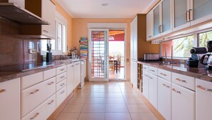 A modern kitchen with white cabinets, granite countertops, and a sliding glass door leading to a dining area. - LUXURY AIR-CONDITIONED VILLA WITH SEA VIEW 5 BED 10 PEOPLE WI FI (Jávea)