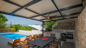 A covered outdoor area with a pool, dining table, chairs, and an outdoor kitchen. - Beautiful home in Glavina Donja (Glavina Donja)