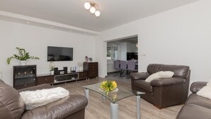 A modern living room with a flat-screen TV, leather sofas, a glass coffee table, and a dining area in the background. - Beautiful home in Glavina Donja (Glavina Donja)