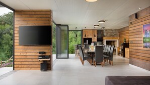 Un interior moderno con comedor, cocina y un televisor grande montado en una pared de madera.