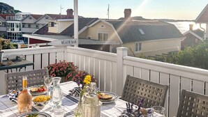 Mesa de comedor preparada con diversos platos y bebidas en un balcón con vistas a un pueblo costero.