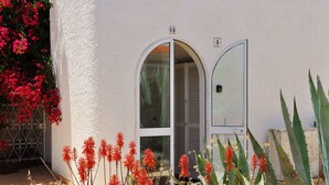 Un bâtiment à la façade blanche, portant le numéro « 03 » et doté d’une porte avec une fenêtre.