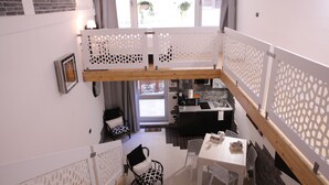 Un apartamento pequeño con balcón, kitchenette y zona de comedor.