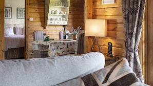 A cozy room with a bed, a table with a lamp, and a view of another room with a bed. - Curlew Lodge - sleeps 6 guests  in 3 bedrooms (Ravenstonedale / Kirkby Stephen)