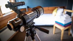 A telescope on a tripod in a room with a bed and a window. - Curlew Lodge - sleeps 6 guests  in 3 bedrooms (Ravenstonedale / Kirkby Stephen)