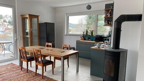 A modern kitchen with a dining area, a built-in stove, and a view of the outside. - Warm magic in the heart of the Black Forest (Titisee-Neustadt)